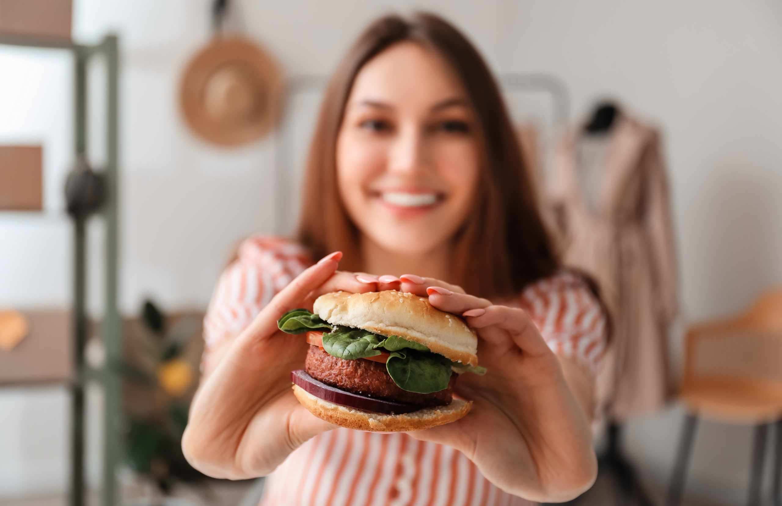 Lady holding a tasty vegan burger at workplace