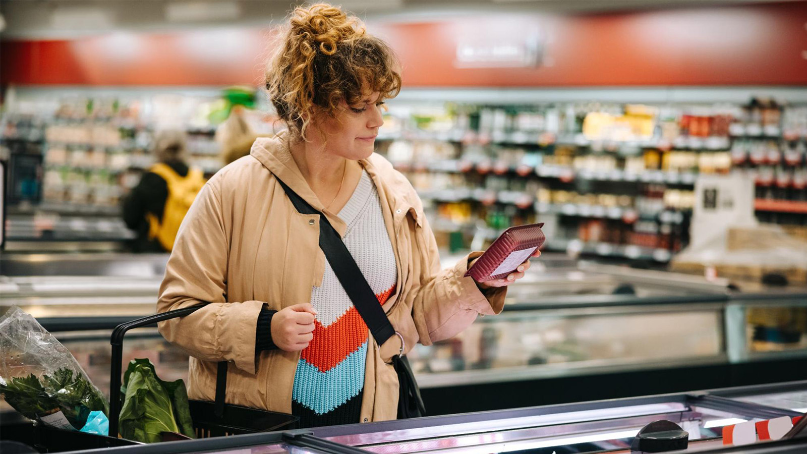 Woman at a grocery store reading a product label.